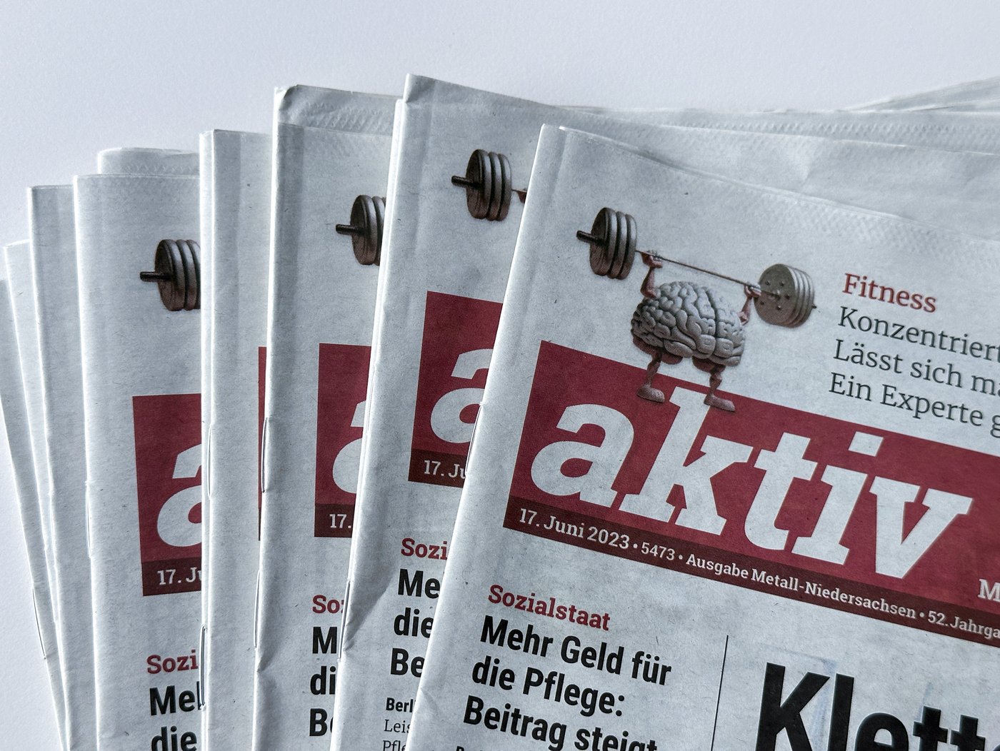 Ein Stapel von Zeitschriften der aktiv - der Fokus liegt auf der linken Oberen Ecke, in der ein Gehirn stilisiert ist, welches Gewichte hebt.